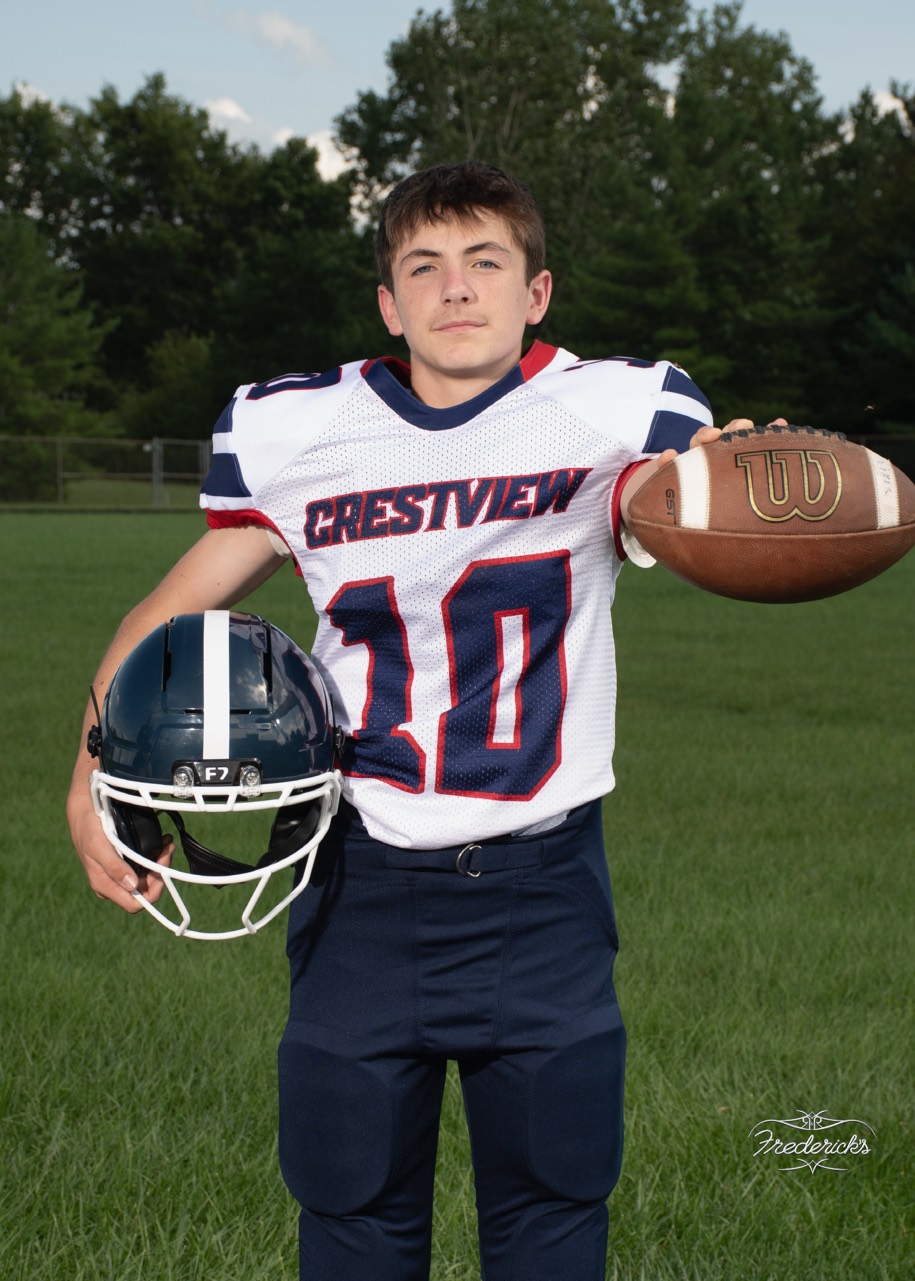 Ben holding a football and helmet in his original football portrait